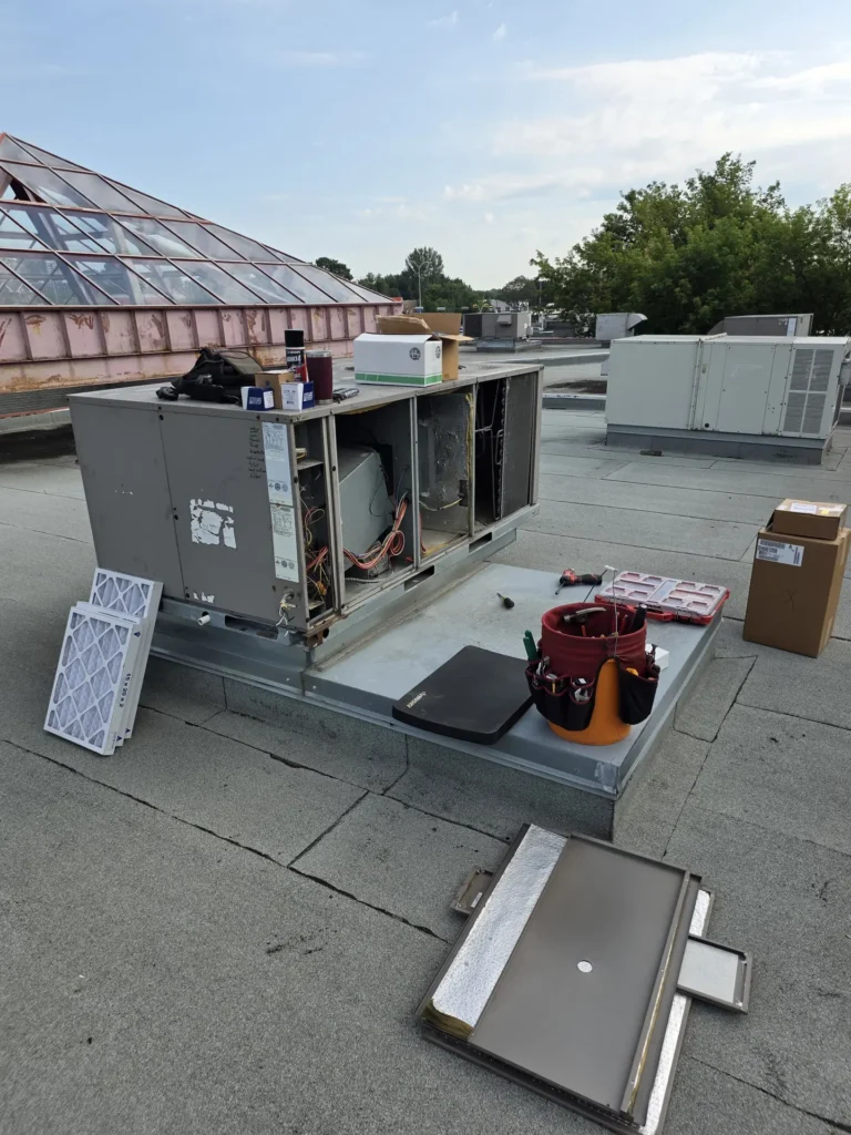 Commercial rooftop unit open for maintenance, filters removed and technician's tools nearby