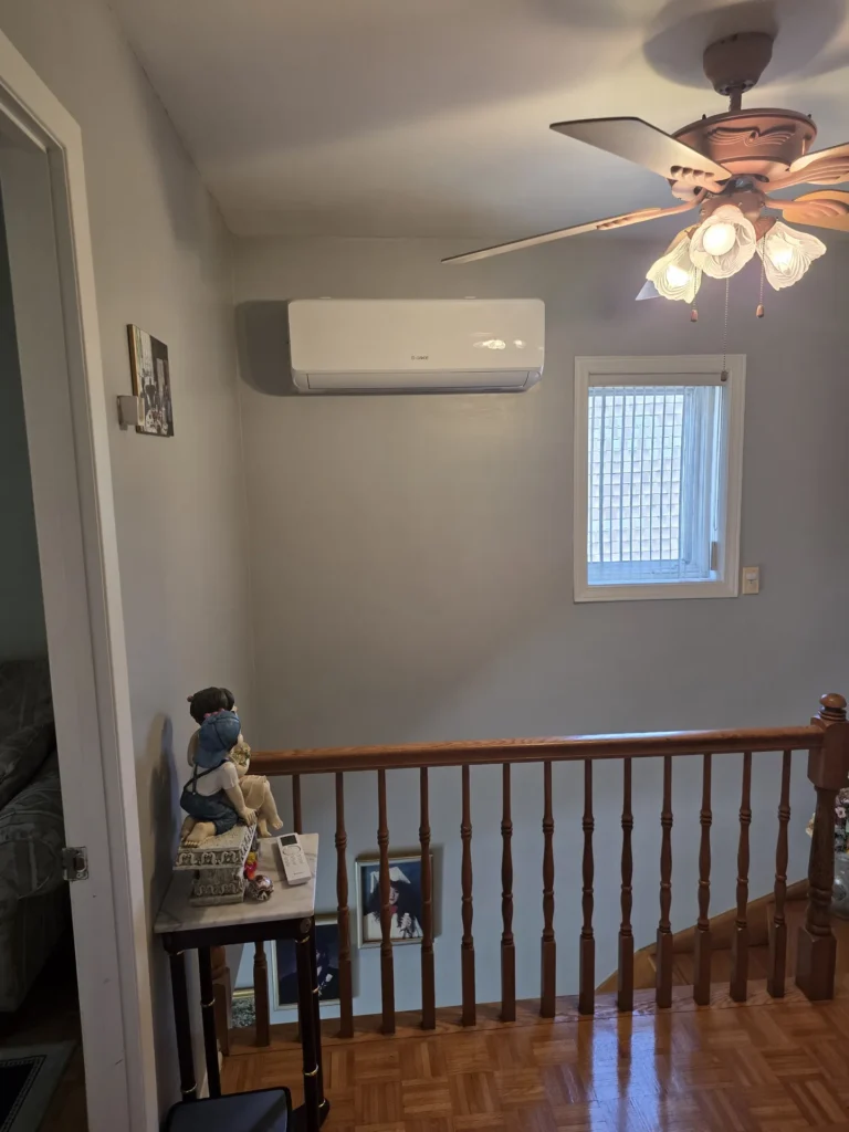 Indoor unit of a wall-mounted heat pump installed at the top of a staircase in a house