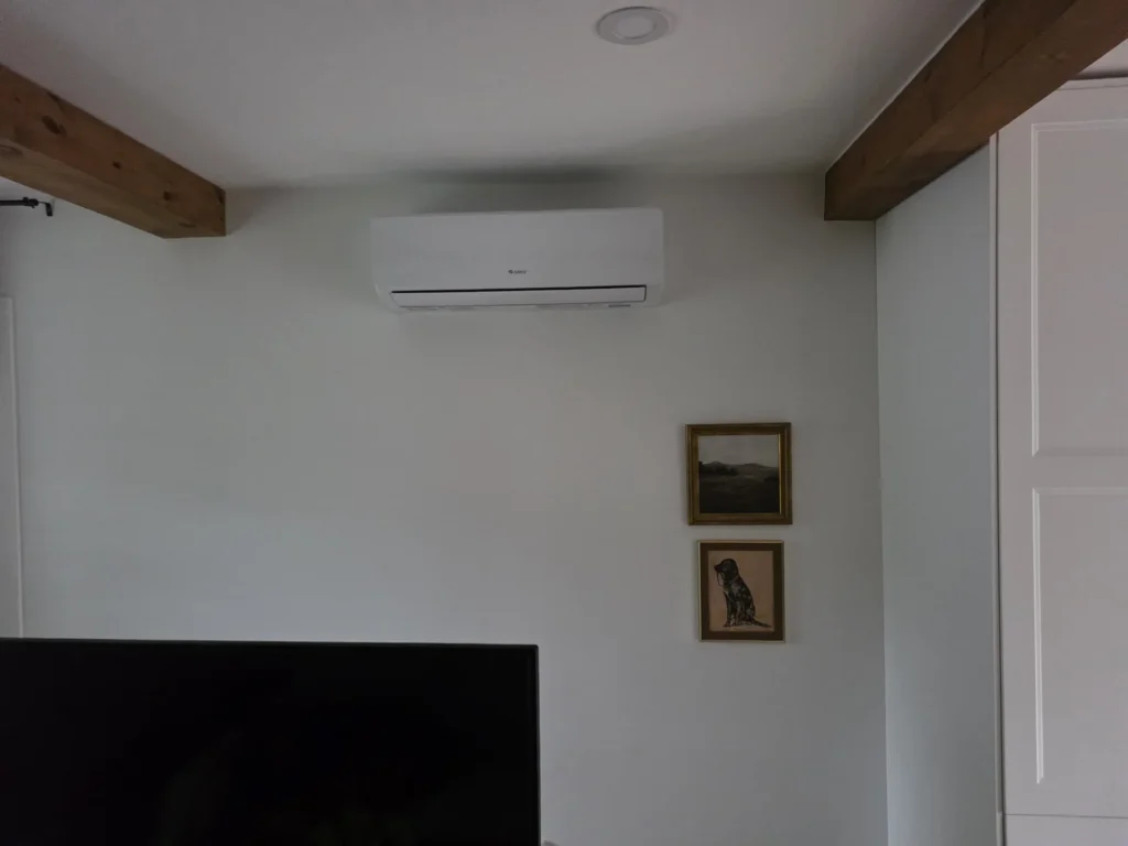 Thermopompe murale installée dans un salon aux poutres de bois apparentes